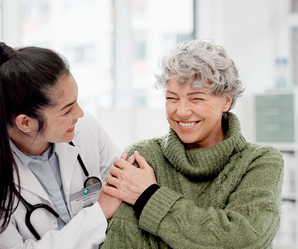 Happy, care and face of a doctor with a woman for medical trust, healthcare and help. Laughing, hug and portrait of a young nurse with a senior patient and love during a consultation at a clinic.