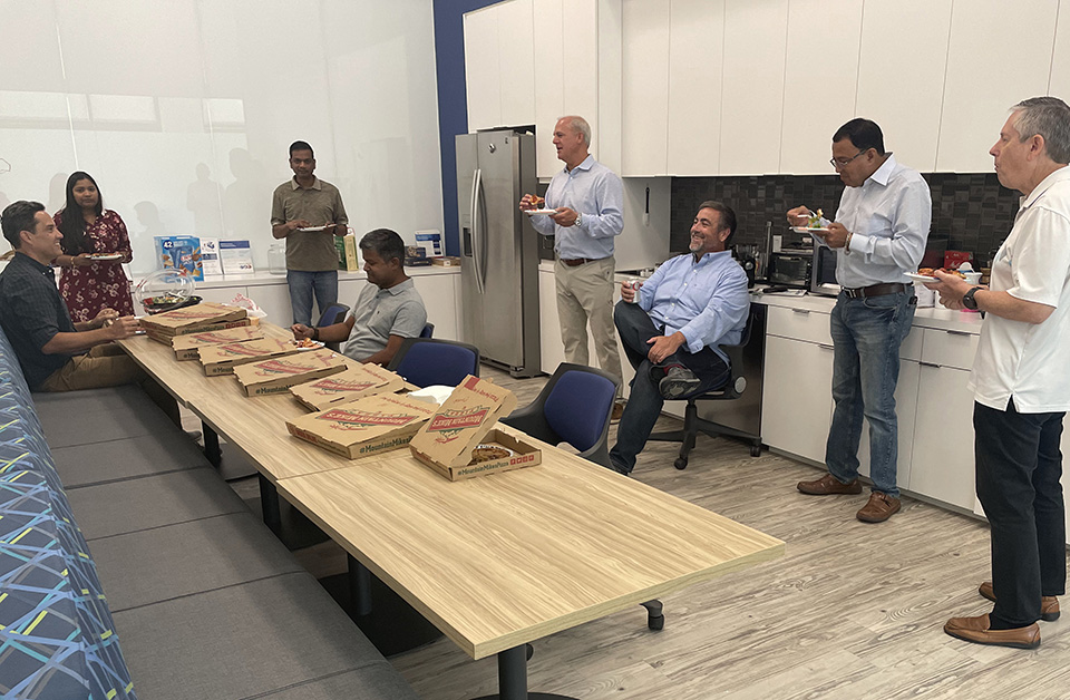 Vital Data Technology employees gathering in the office kitchen for a complementary pizza lunch.