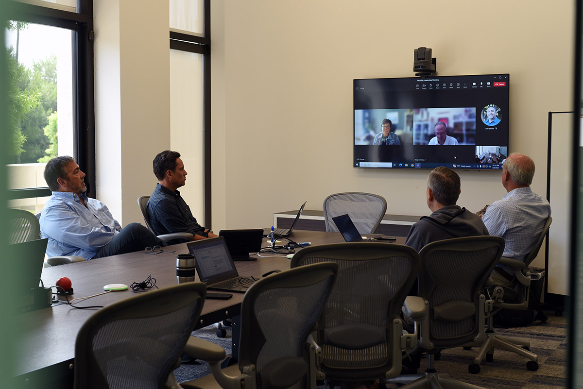 Vital Data Technology Executive Team sitting around a conference table on a conference call with remote employees.